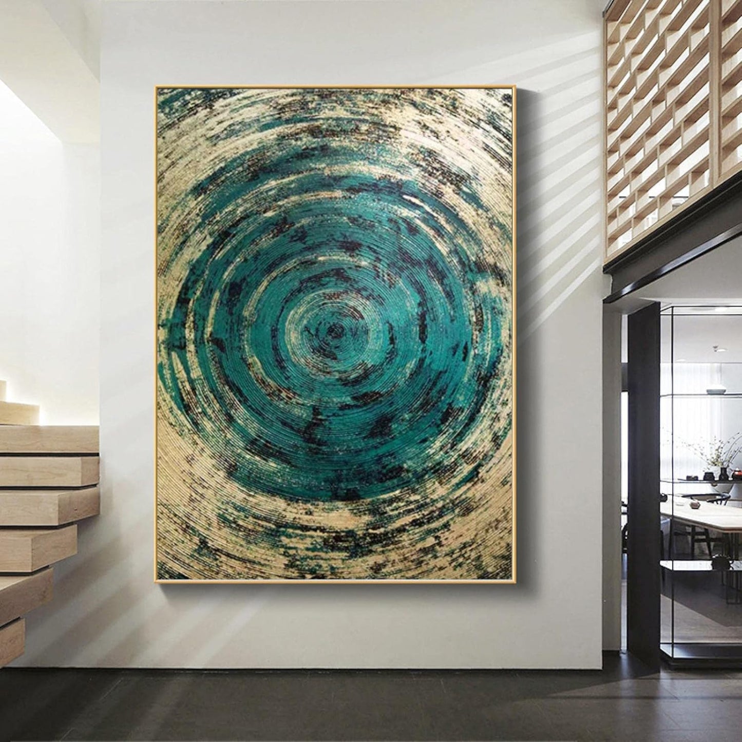 Abstract art piece with concentric circular patterns in teal and beige on a white wall.