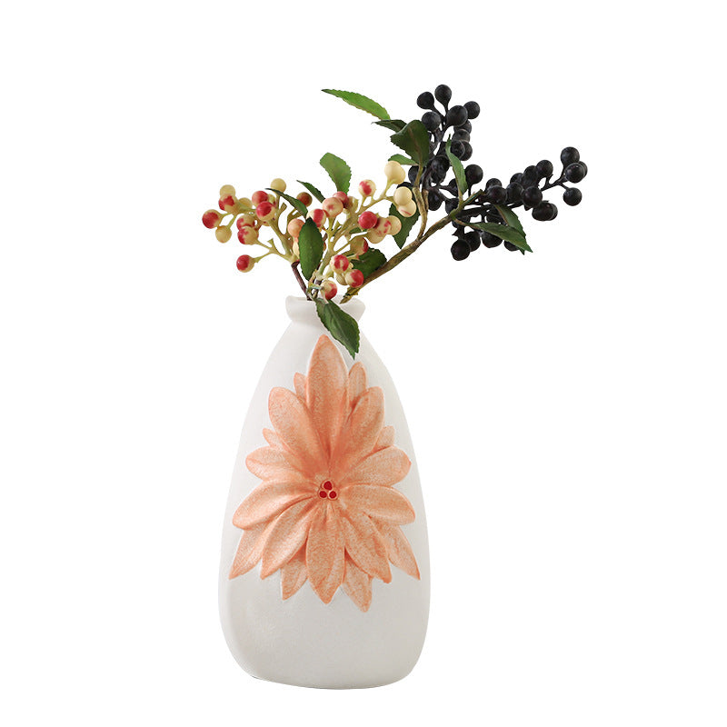 White vase with a large orange flower and smaller green and red flowers on a white background