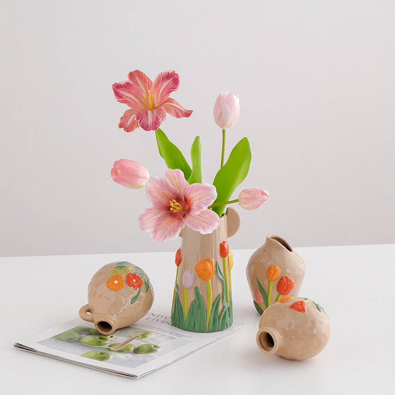 Set of ceramic vases with floral designs and pink flowers on a white surface.