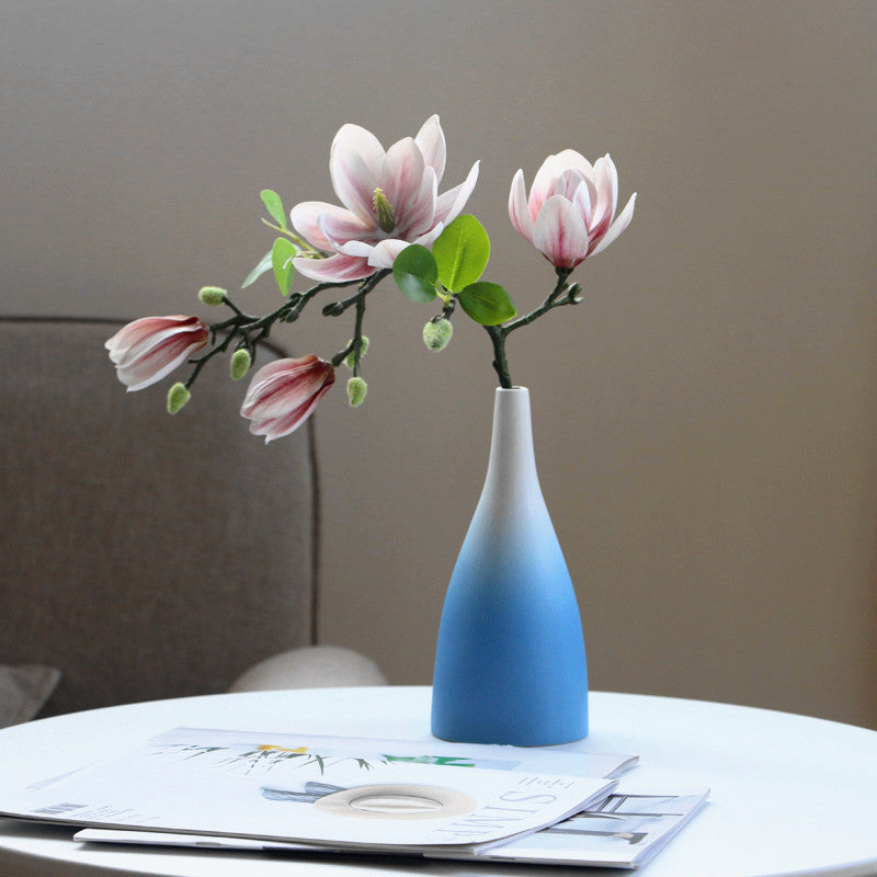 Blue vase with pink flowers on a table against a neutral background