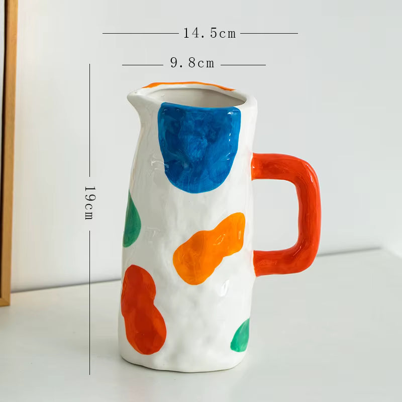 Ceramic pitcher with colorful abstract design and measurements on a white background