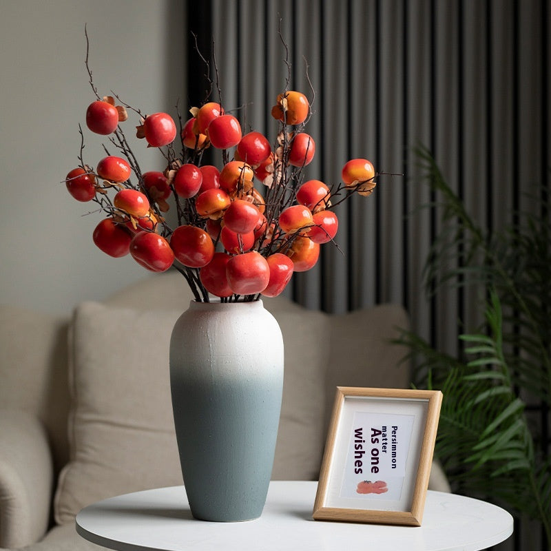 Decorative vase with red and orange berries on a table in a living room setting.