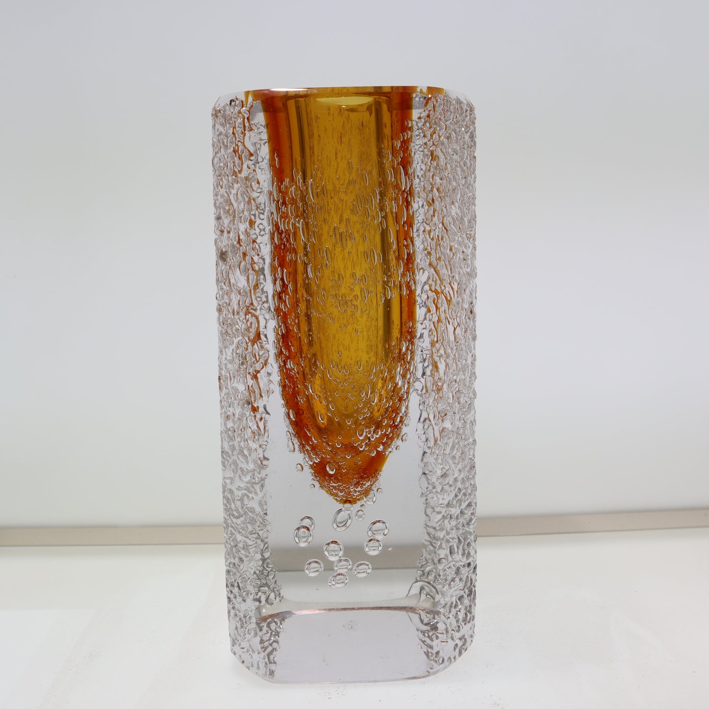 Glass vase with amber-colored top and textured base on a white background