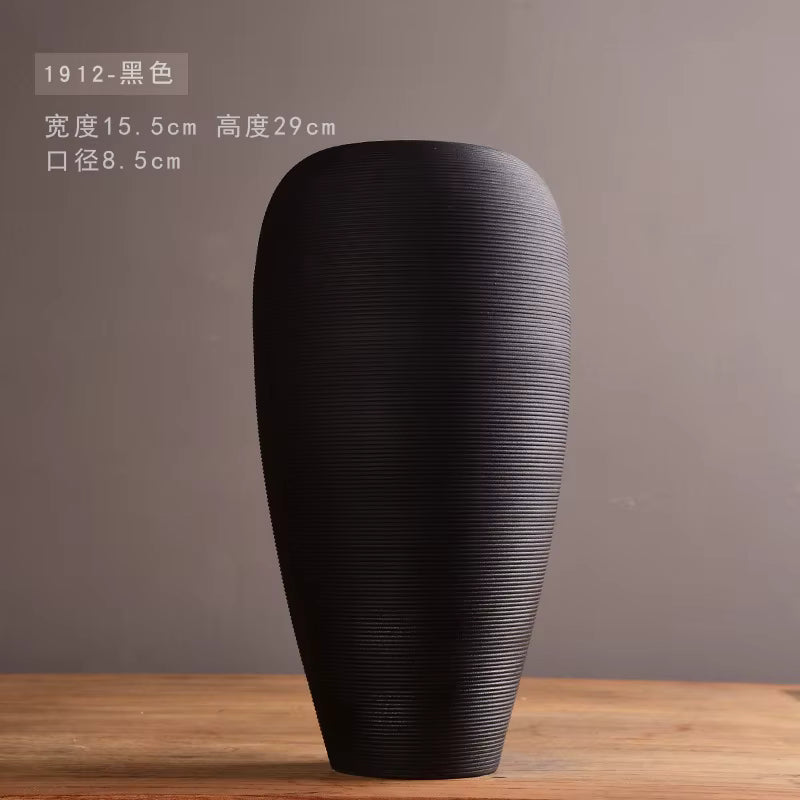 Black textured vase on a wooden surface with a gray background