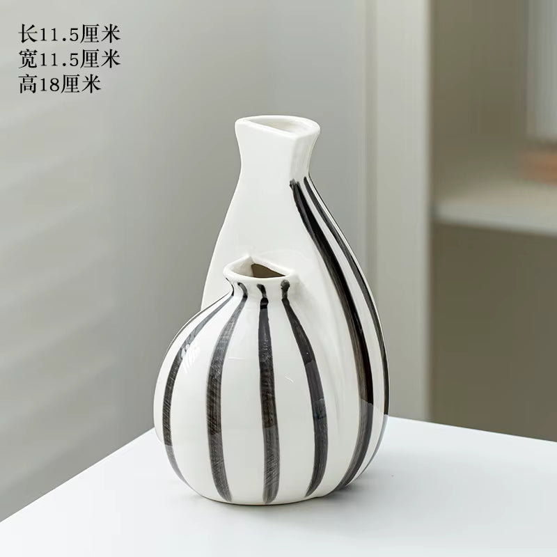 Two ceramic vases with black stripes on a white surface