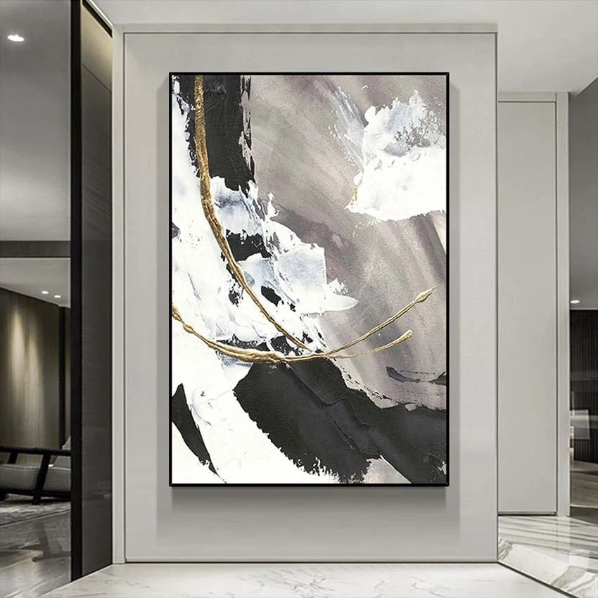 Abstract art piece with black, white, and gold tones on a wall in a modern interior setting.