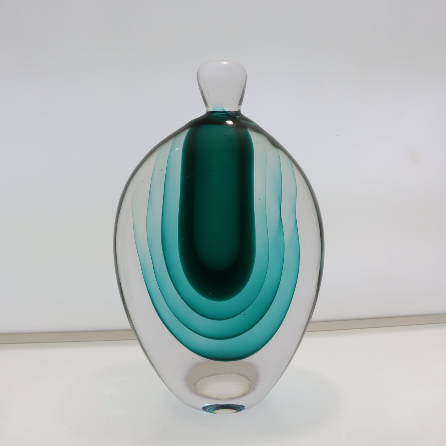Glass vase with concentric green and clear layers on a white background