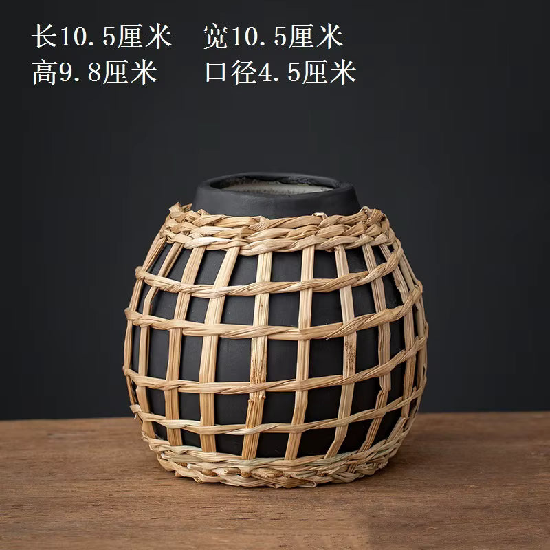 Black vase with woven basket design on a wooden surface and dark background