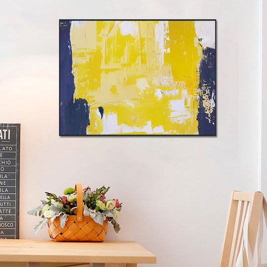 Abstract art piece with yellow and blue colors on a wall above a table with a floral basket.