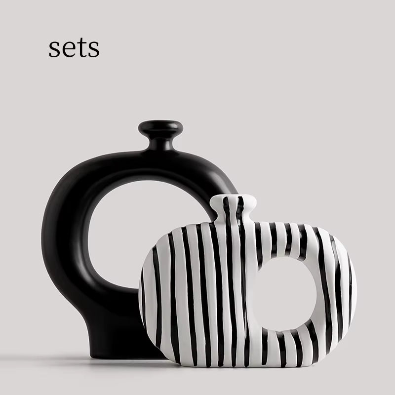 Two ceramic vases, one black and one with black and white striped pattern, on a light gray background.