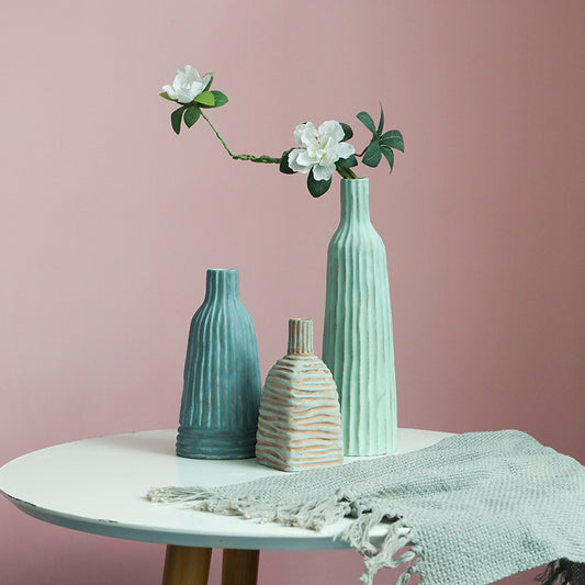 Three ceramic vases on a table with a pink background