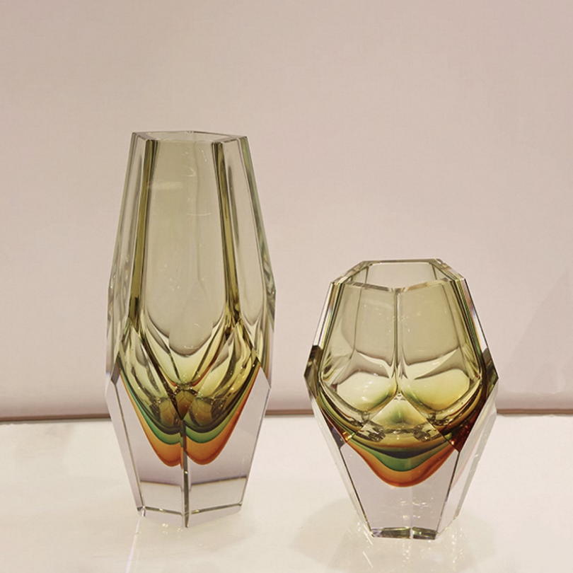 Two geometric glass vases on a light surface with a neutral background