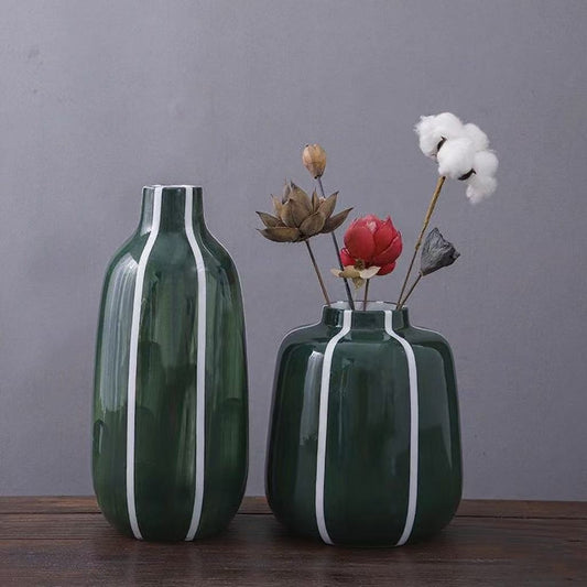 Two green vases with white stripes on a wooden surface against a gray background