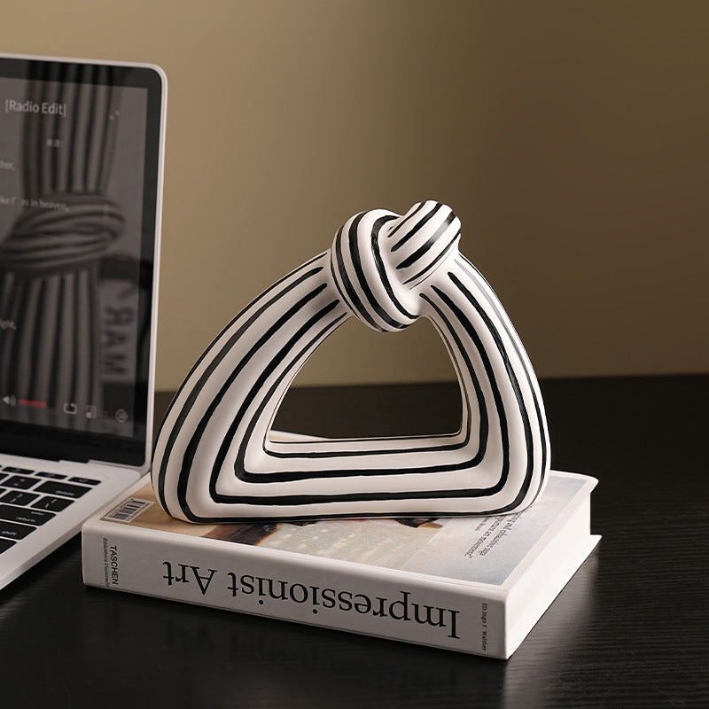 Decorative sculpture of stacked triangles on a book with a laptop in the background