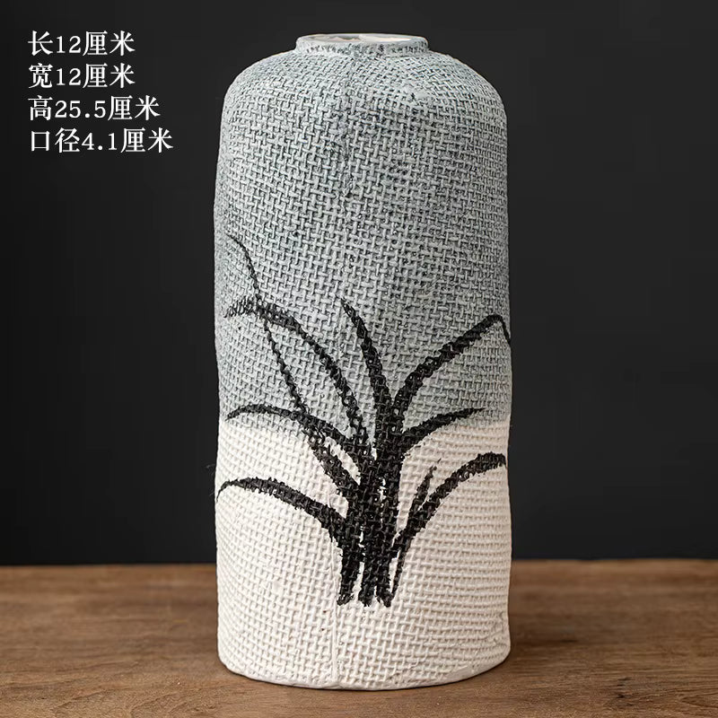 Textured vase with black plant design on a wooden surface and dark background