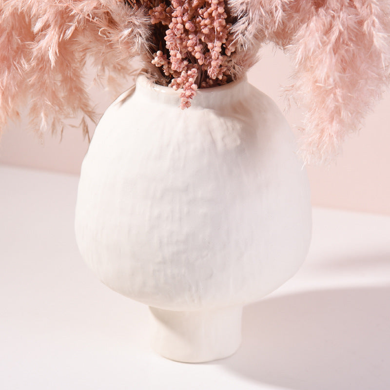 White vase with pink flowers against a soft pink background