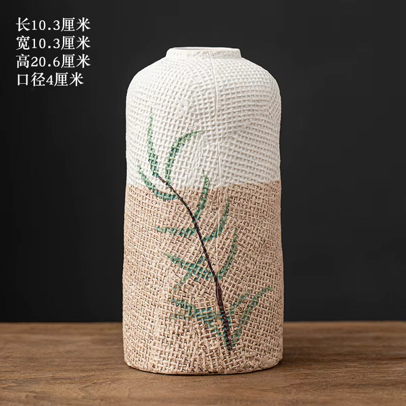 Textured vase with green leaf design on a wooden surface and black background