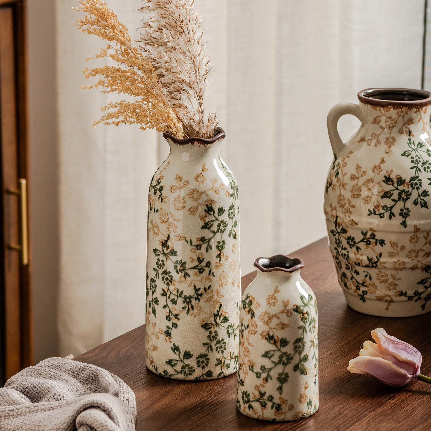 Set of decorative ceramic vases with floral patterns on a wooden surface.