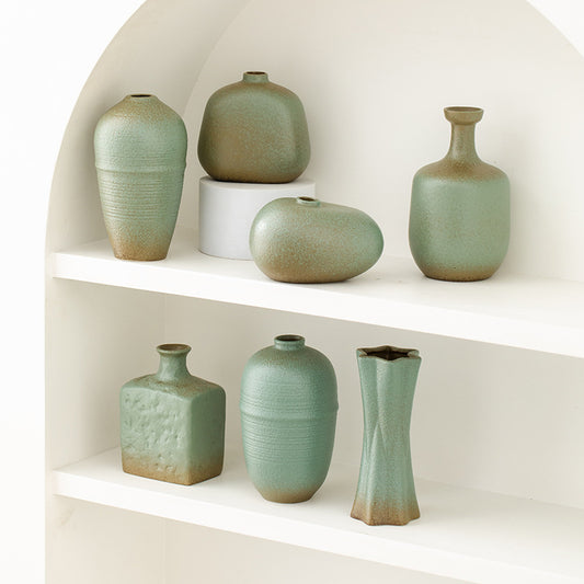 Set of green ceramic vases on a white shelf