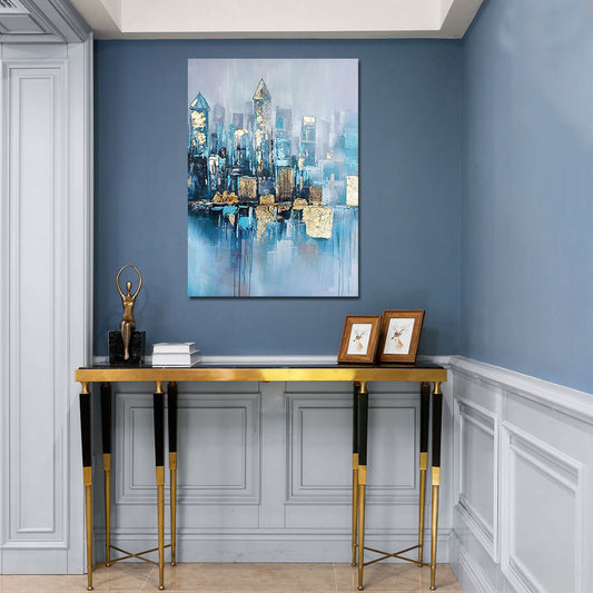 Decorative interior with a cityscape painting on a blue wall, gold console table, and framed pictures.