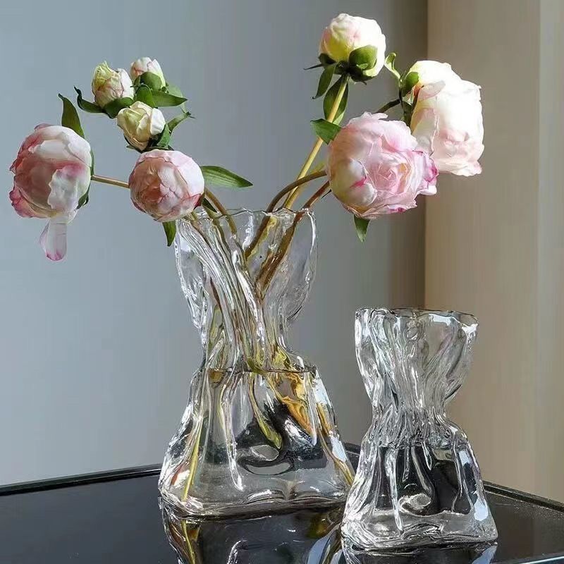 Clear glass vases with pink flowers on a reflective surface