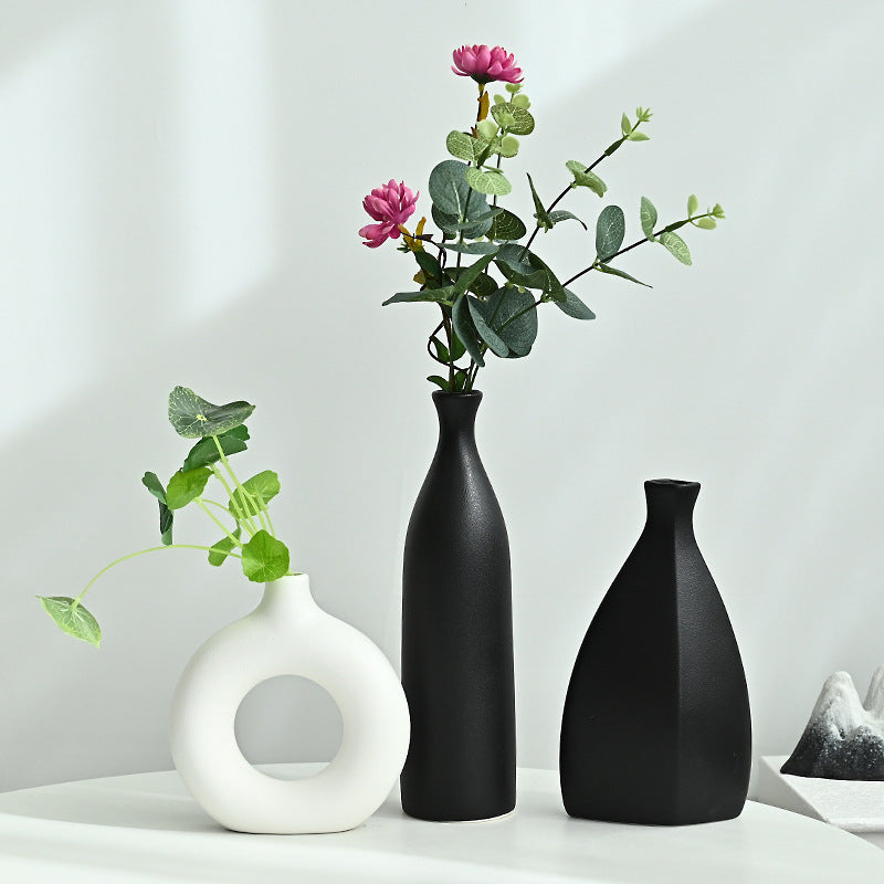 Three vases of different shapes and colors on a white surface with a light gray background