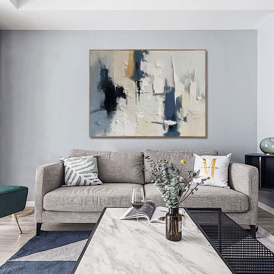 Modern living room with a gray sofa, abstract painting, and decorative items.