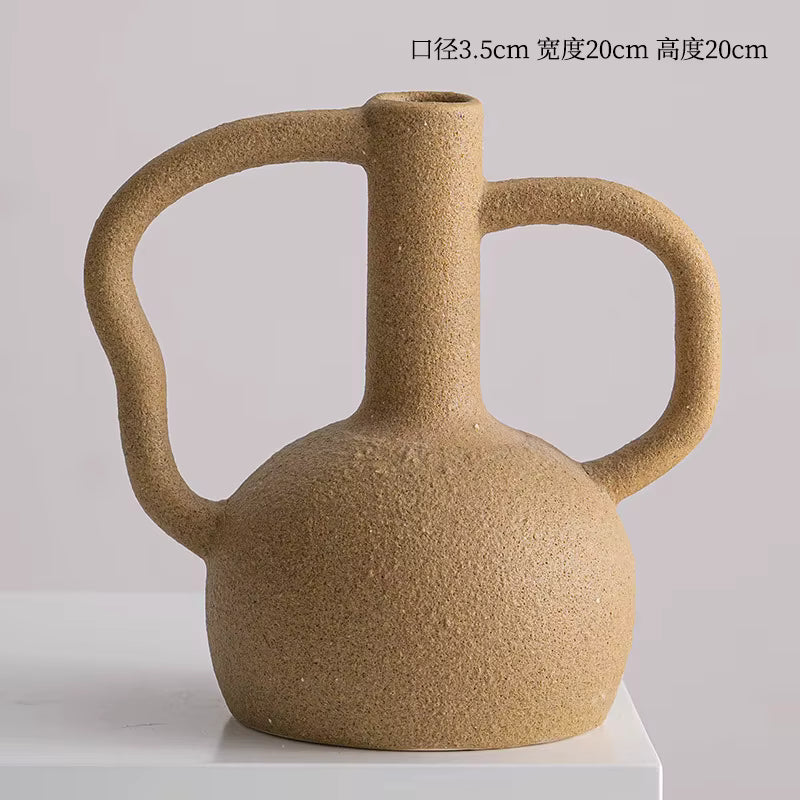 Brown ceramic vase with handles on a white platform against a light gray background