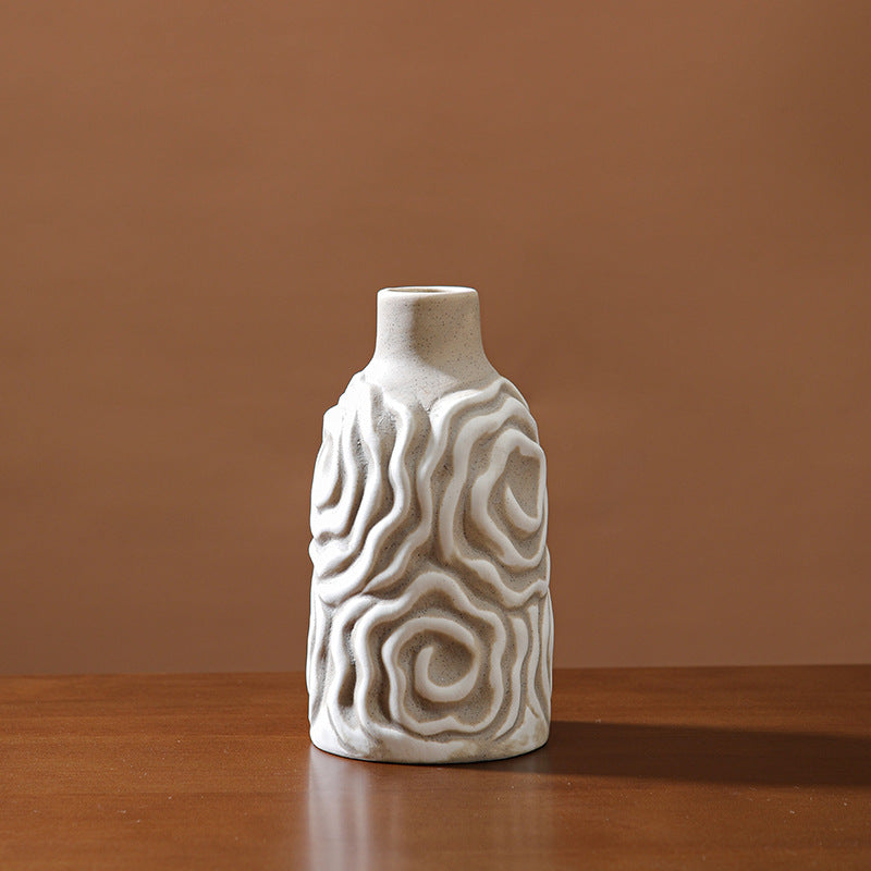 White ceramic vase with wavy patterns on a wooden surface and brown background