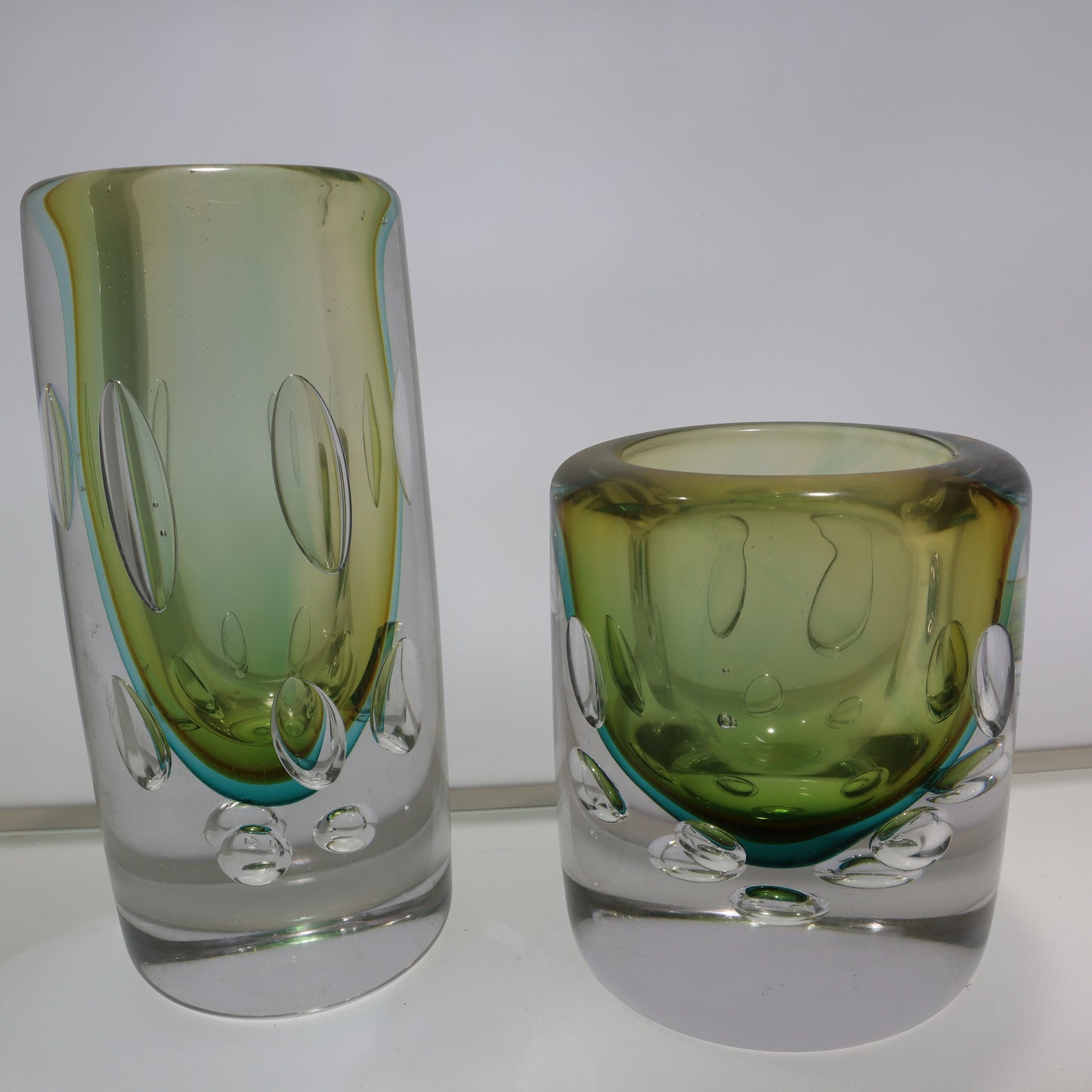 Two green glass tumblers on a white background