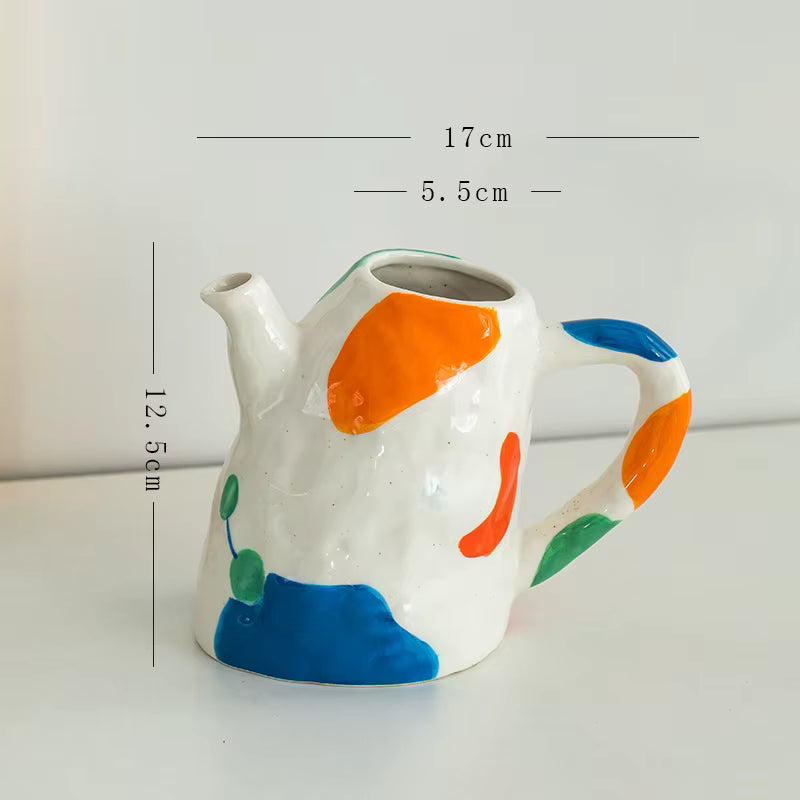 Ceramic teapot with colorful design and measurements on a white background