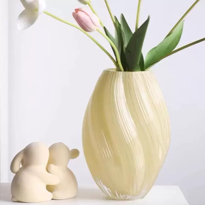 Beige vase with flowers and two small animal figurines on a light background