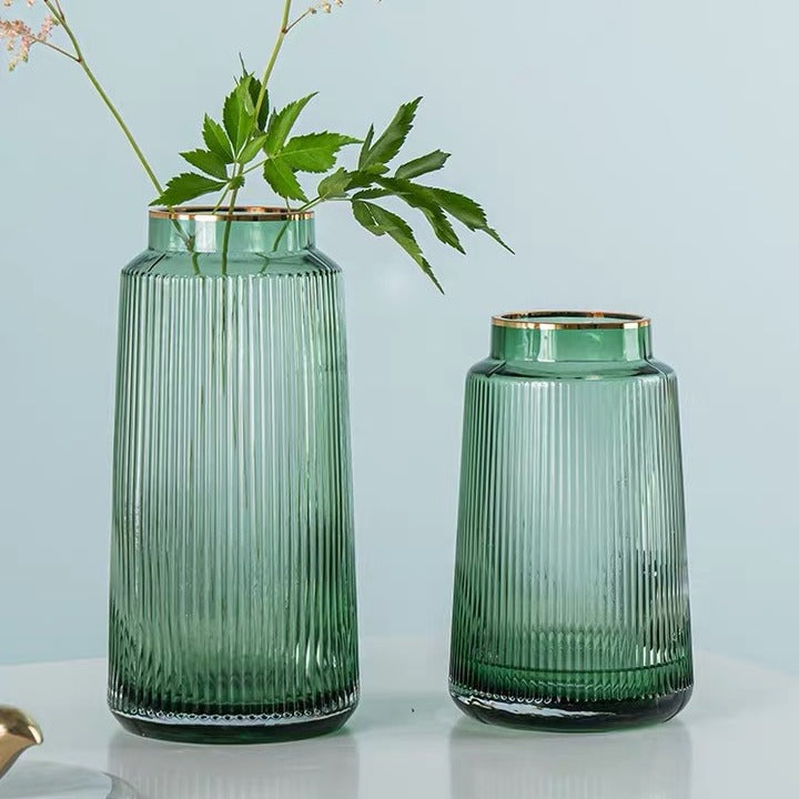 Two green glass vases with ribbed texture on a light blue background