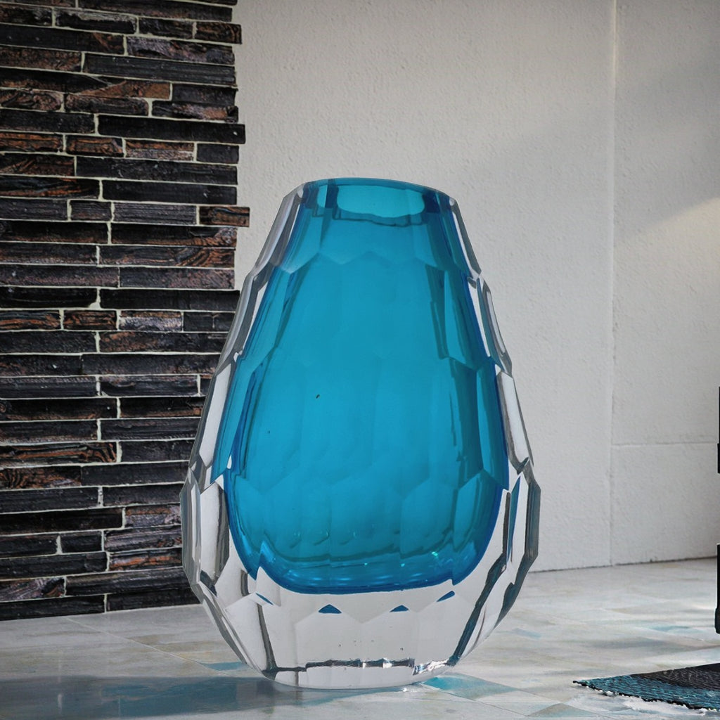 Blue glass vase with geometric design against a brick wall