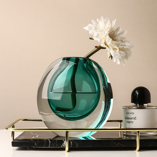 Green glass vase with a white flower on a decorative stand against a beige background