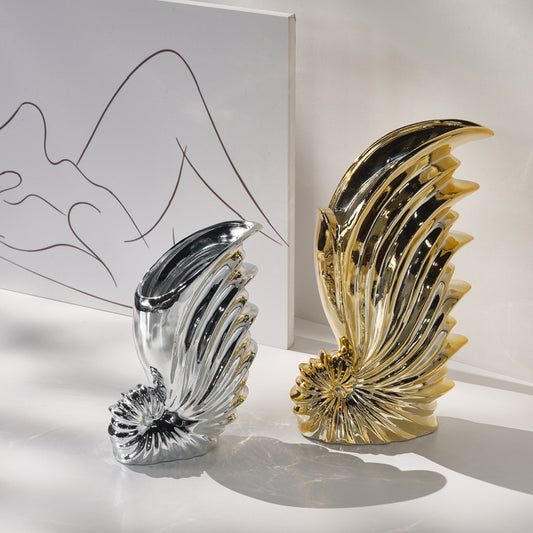 Decorative vases, one silver and one gold, on a light surface with a white background.