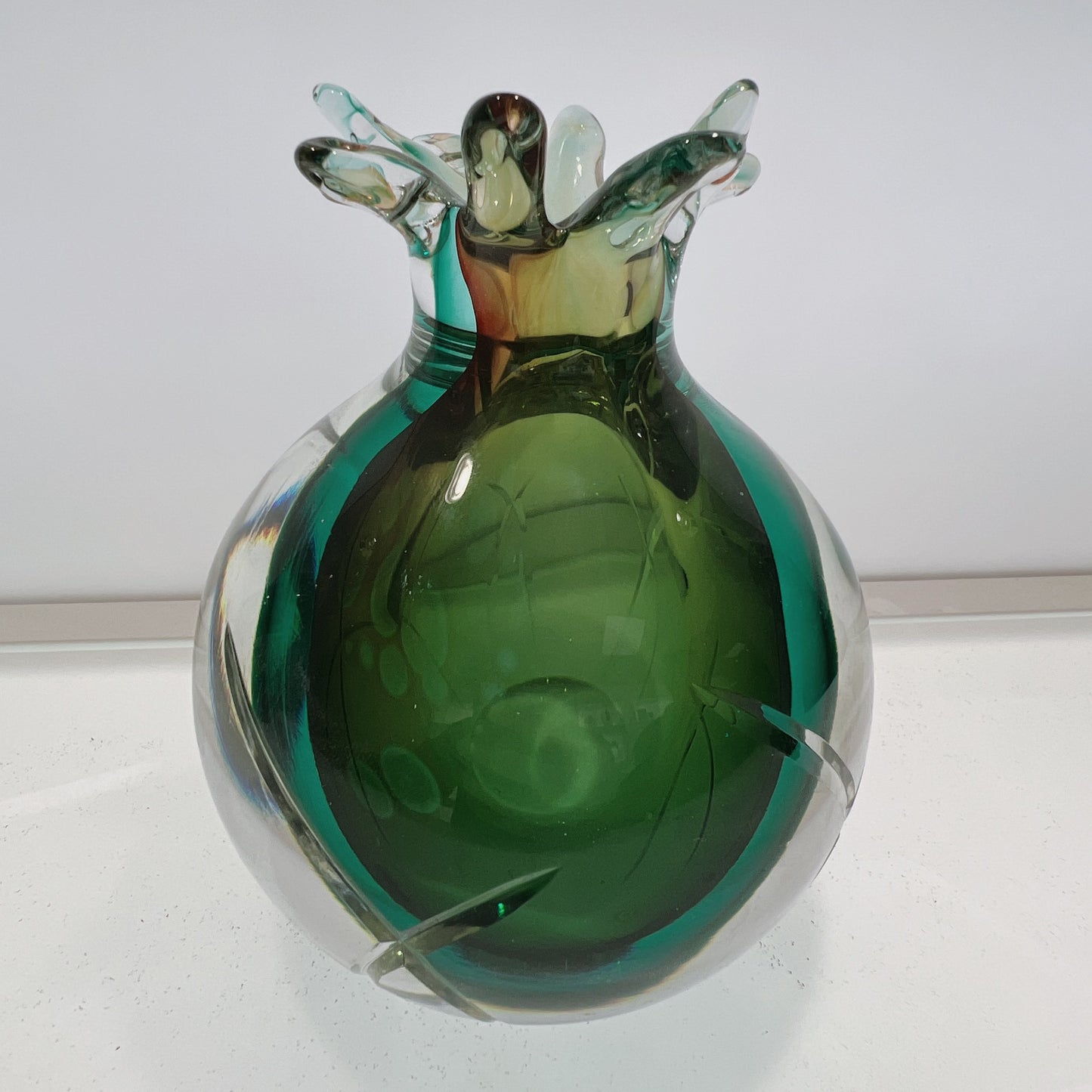 Green glass vase with a textured surface on a white background