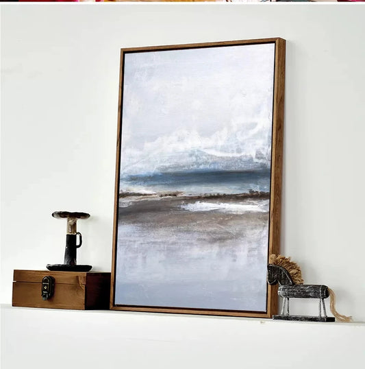 Framed beach scene print on a white wall with decorative items below.