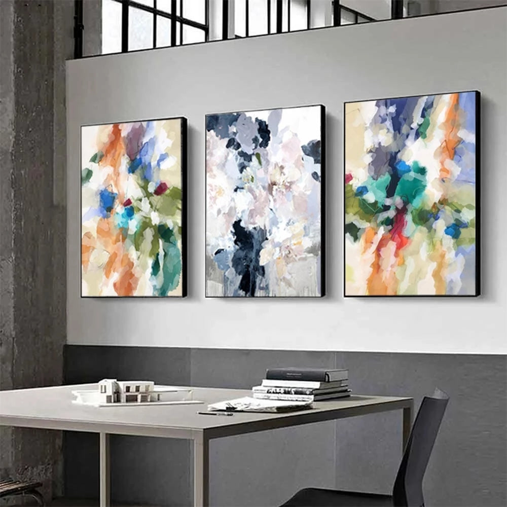 Three abstract art pieces on a wall above a desk.