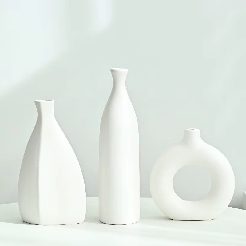 Three white ceramic vases of different shapes on a light gray background