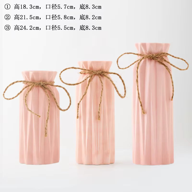 Three pink ceramic vases with twine bows on a white background