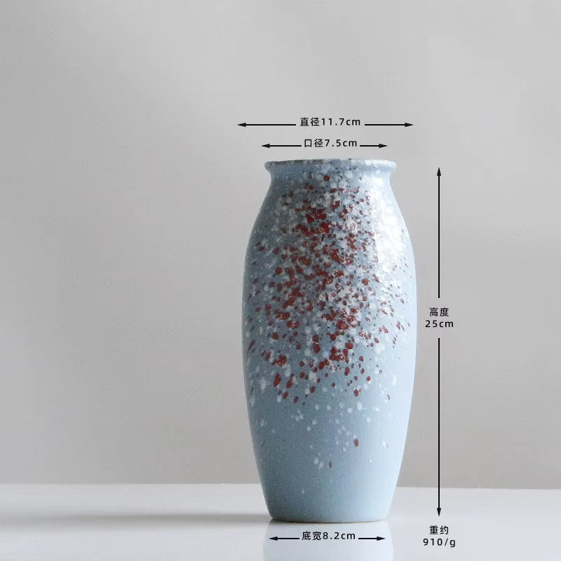 Blue ceramic vase with red speckles and measurements on a gray background