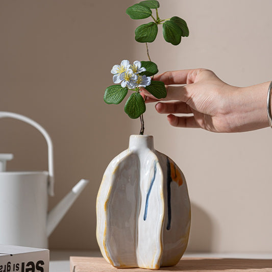 Person placing a plant into a ceramic vase with a white background