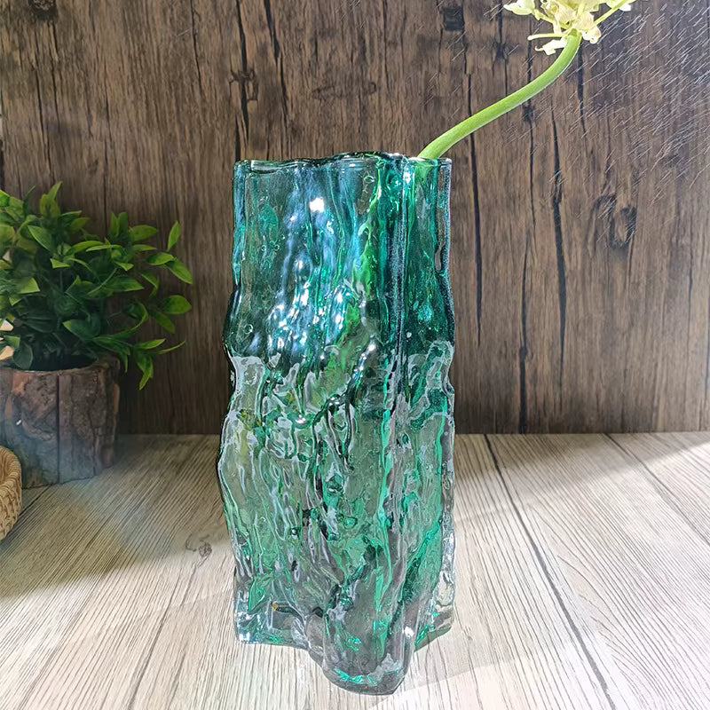 Green glass vase with wavy texture on a wooden surface with a wooden background