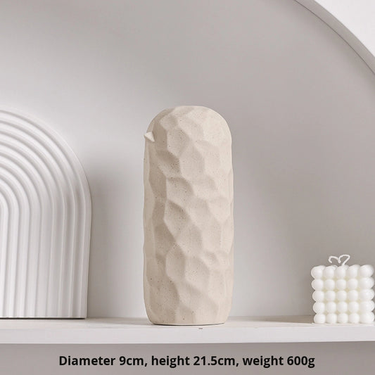 Beige ceramic vase on a white shelf with architectural elements in the background