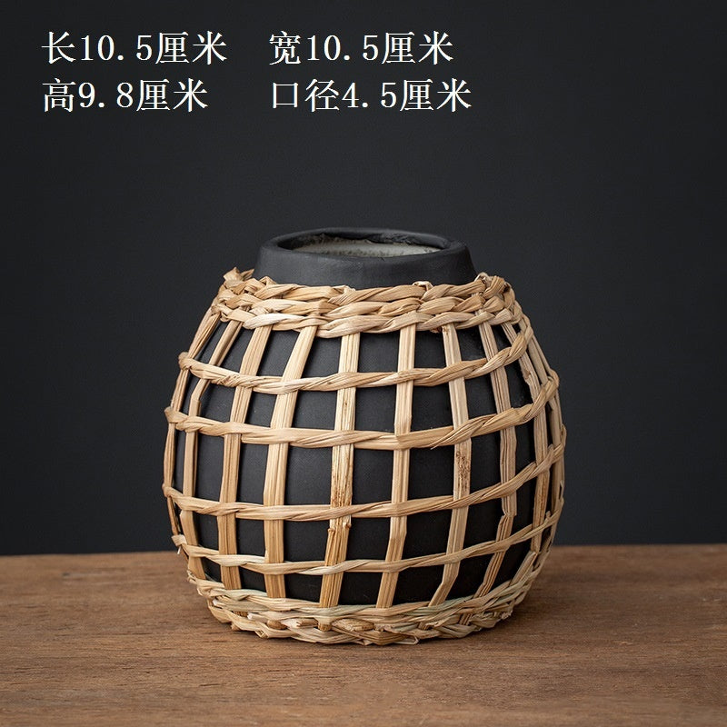 Black vase with woven wicker design on a wooden surface and dark background