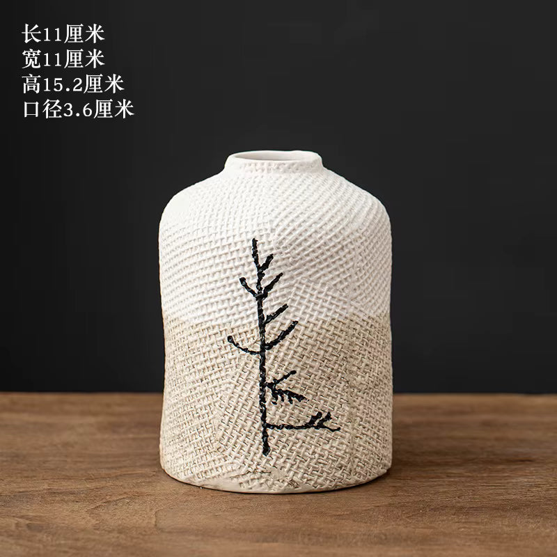 Textured vase with embroidered design on a wooden surface and dark background