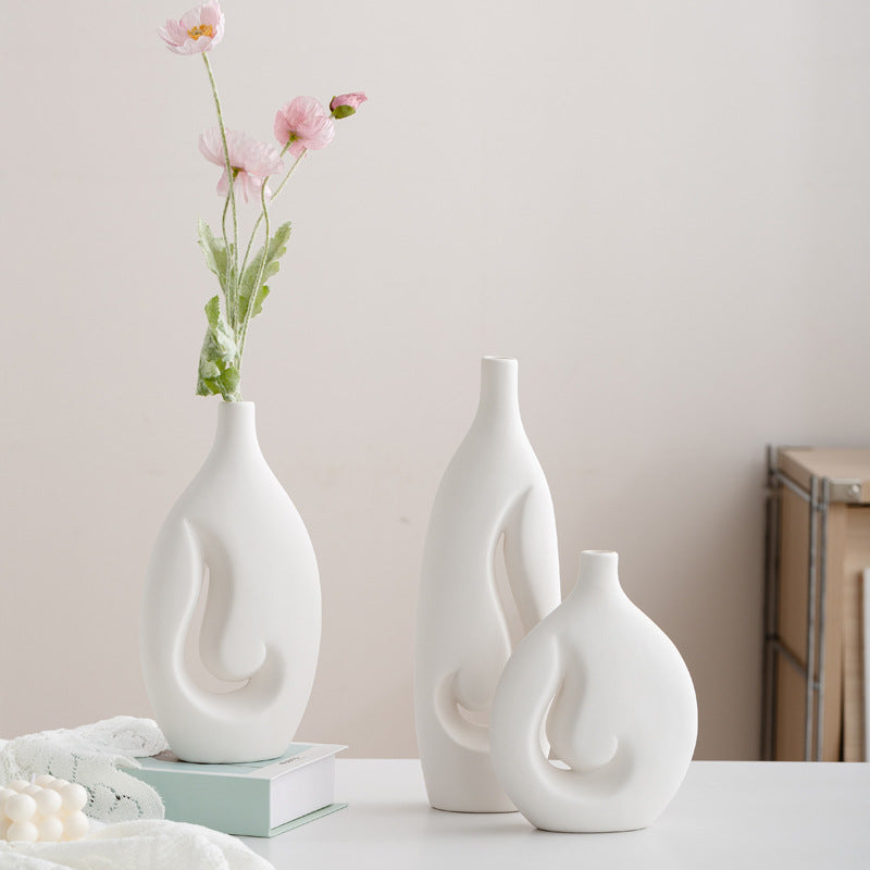 Three white ceramic vases on a table with a light background