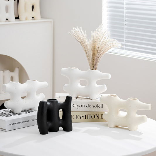 Decorative ceramic pieces on a shelf with books and a vase.