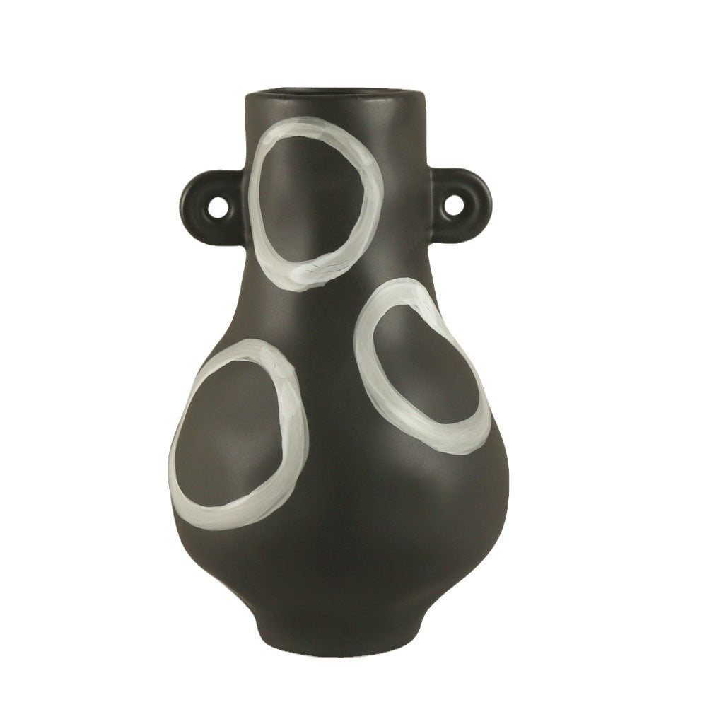Black vase with white circular designs on a white background